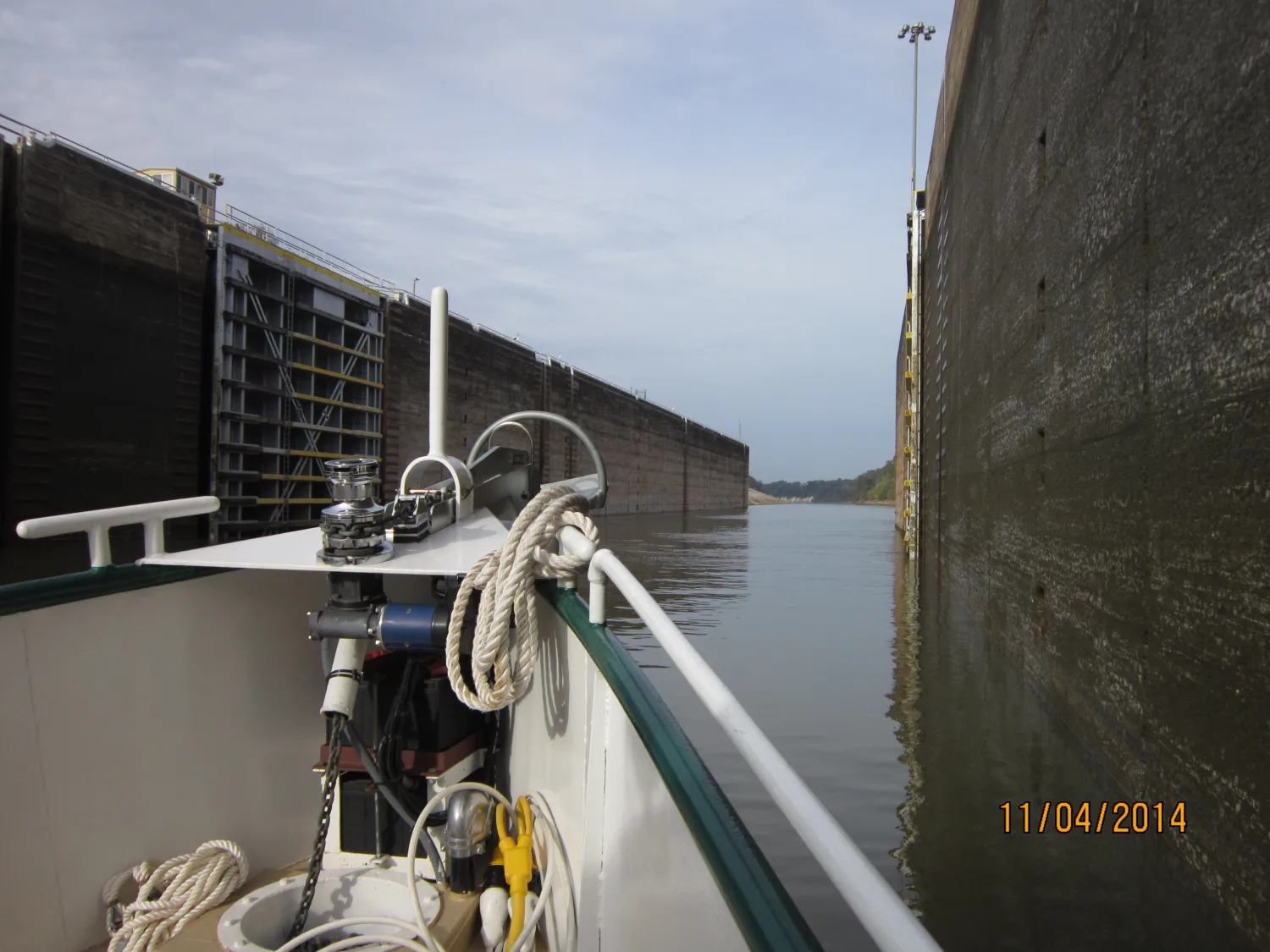 Sage's bow and starboard rail passing close to a tall lock wall