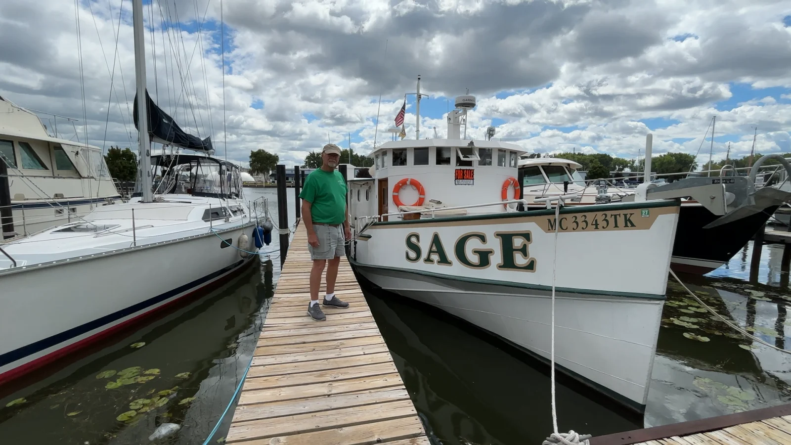 Jim standing aboard Sage beside her nameplate